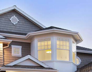 Bay window shown on upper floor of beige sided coastal designed house by home builder in Ocean County
