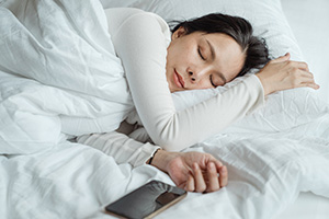Woman cozy in bed knowing she'll avoid heating repair in Belmar this winter